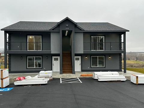 A grey two story house with a balcony on the second floor.