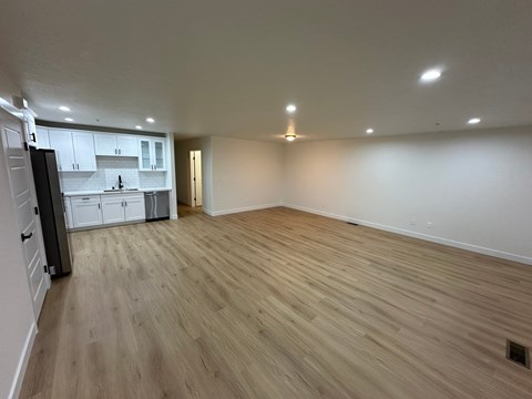 A kitchen with white cabinets and a wooden floor.