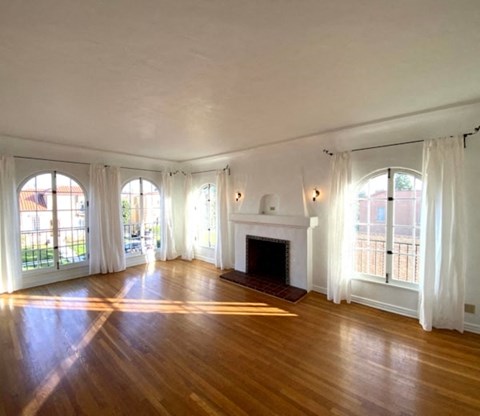 A large room with a fireplace and wooden floors.