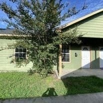 A green house with a tree in front.
