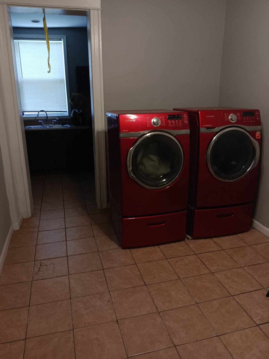 Two red washing machines in a laundry room.