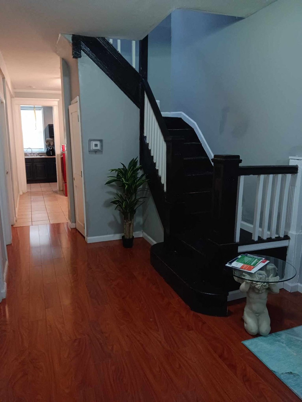 A hallway with a wooden floor and a staircase.