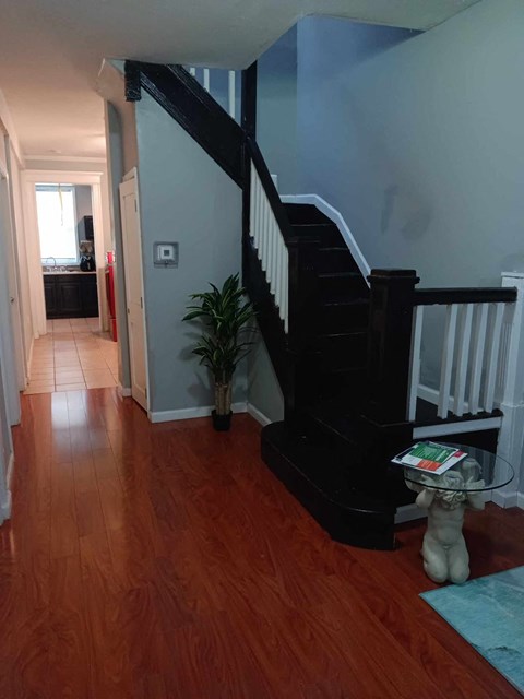 A hallway with a wooden floor and a staircase.