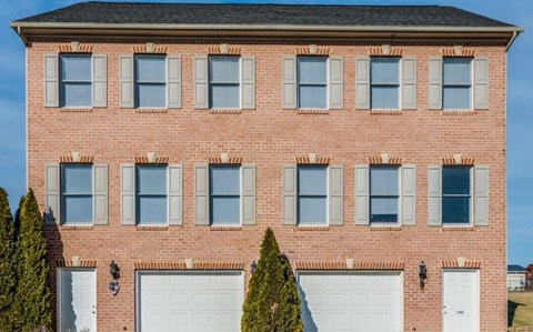 A red brick house with white garage doors and windows.