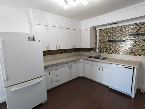 A kitchen with white cabinets and a white fridge.