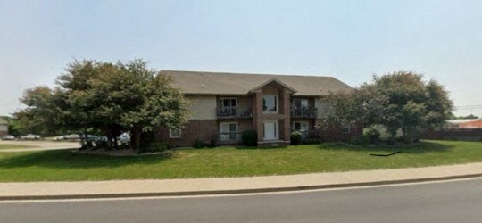 A two-story brick house with a brown roof and a white door.
