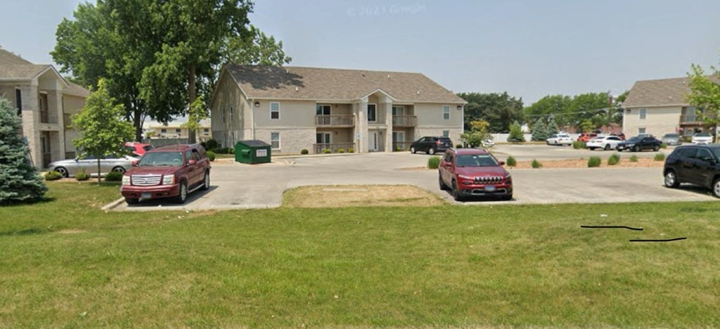 A large house with a driveway and cars parked in front.