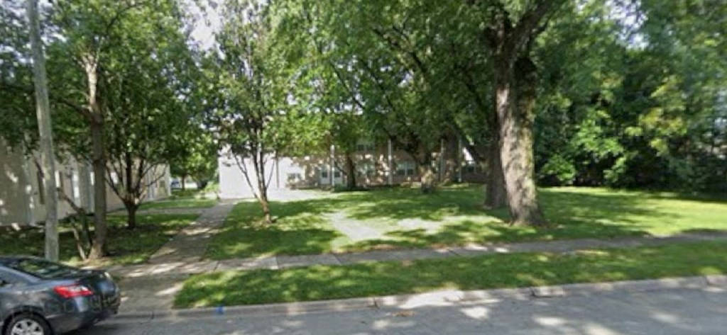 A tree-lined street with a parked car on the side.