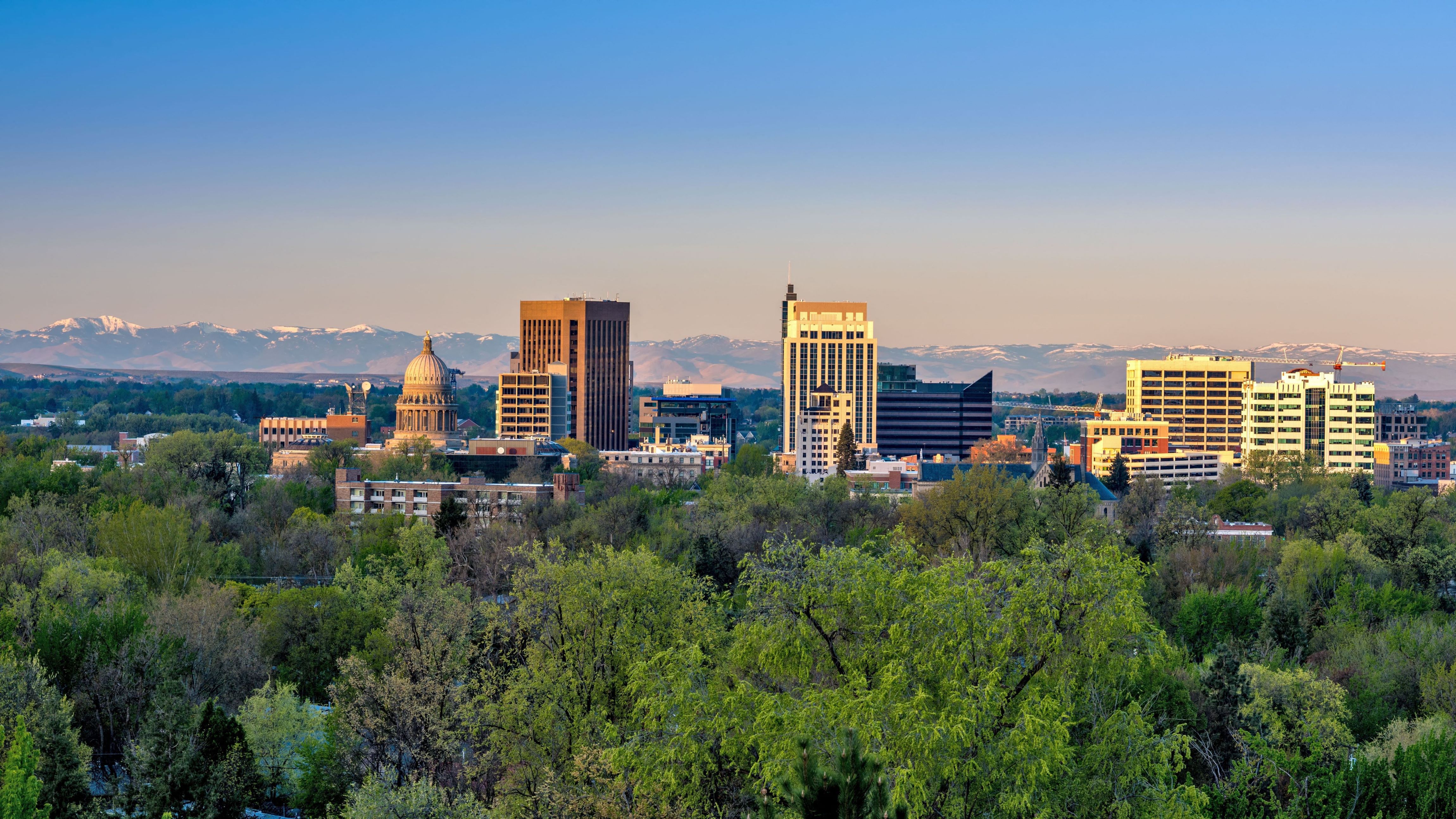 A cityscape with a mountain range in the background and a large building with a golden dome in the foreground.