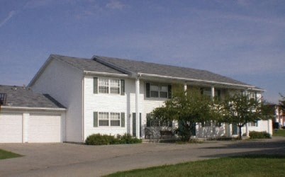 A white house with a grey roof and a garage door.