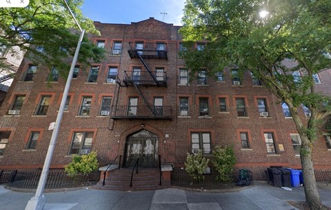 A red brick building with a black iron gate in front.