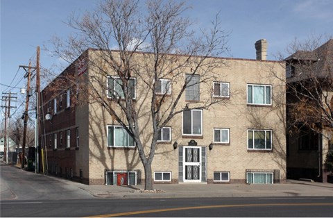 A large building with a red door is situated on a street.