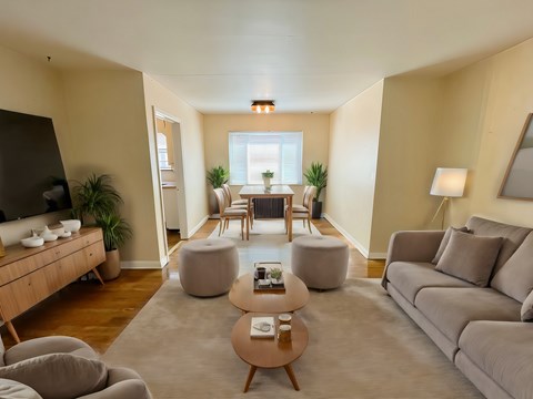 A living room with a grey couch, a wooden coffee table, and a large window.