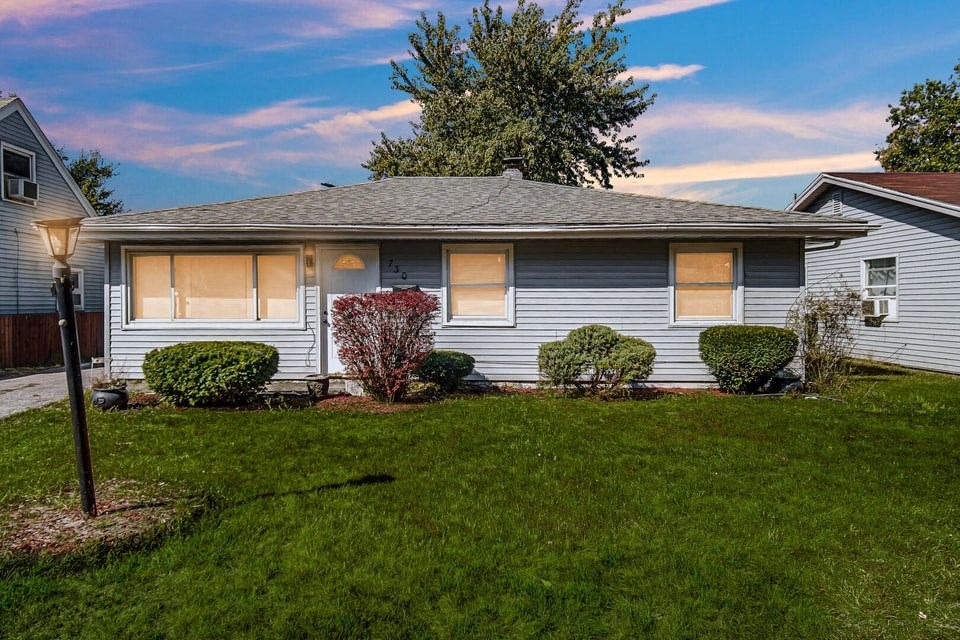 A house with a grey roof and a green lawn in front.
