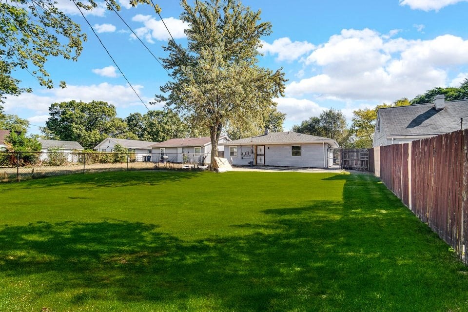 A backyard with a green lawn and a tree.