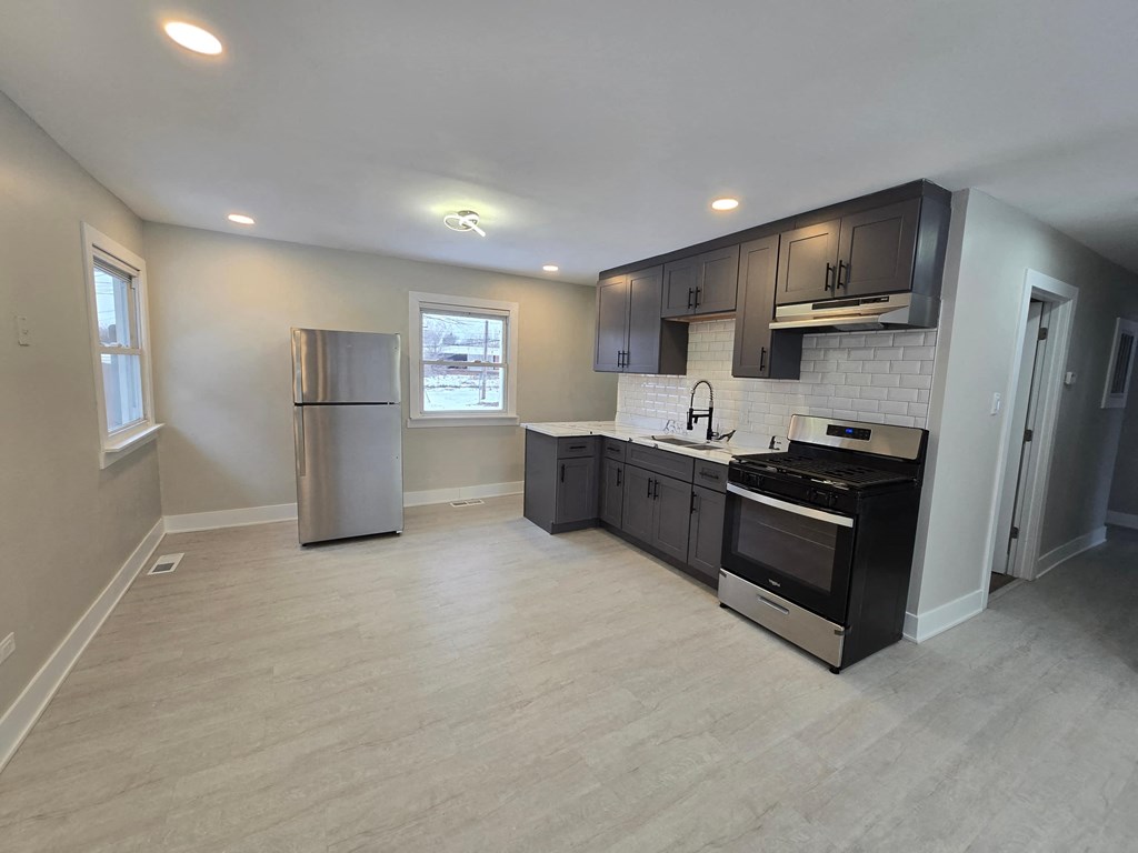 A kitchen with a refrigerator, oven, and sink.