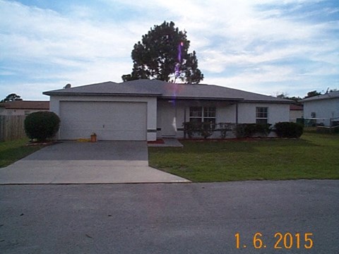 A house with a driveway and a tree in front of it.