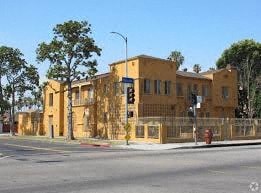 A yellow building is situated on a street corner with a traffic light in front of it.