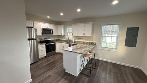 A kitchen with a refrigerator, microwave, oven, and cabinets.