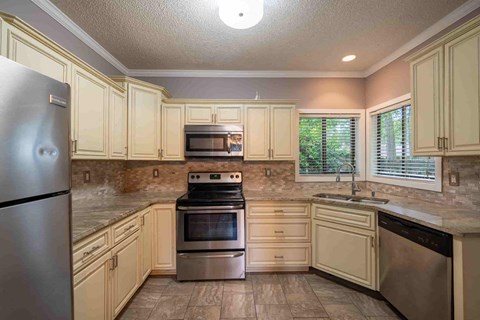 A kitchen with a refrigerator, oven, and sink.