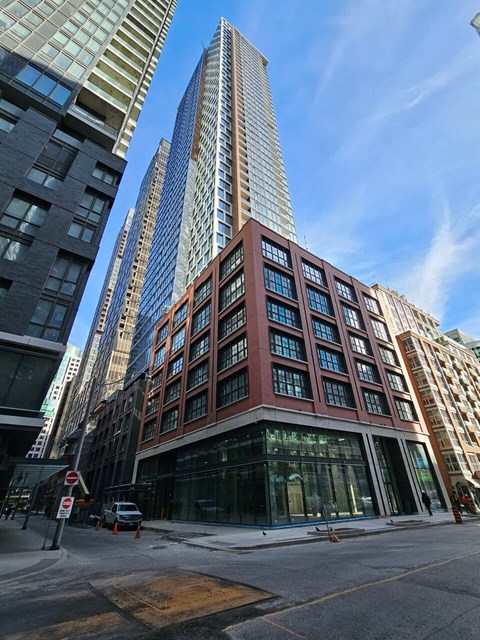 A tall building with a red brick facade stands in front of two taller buildings.