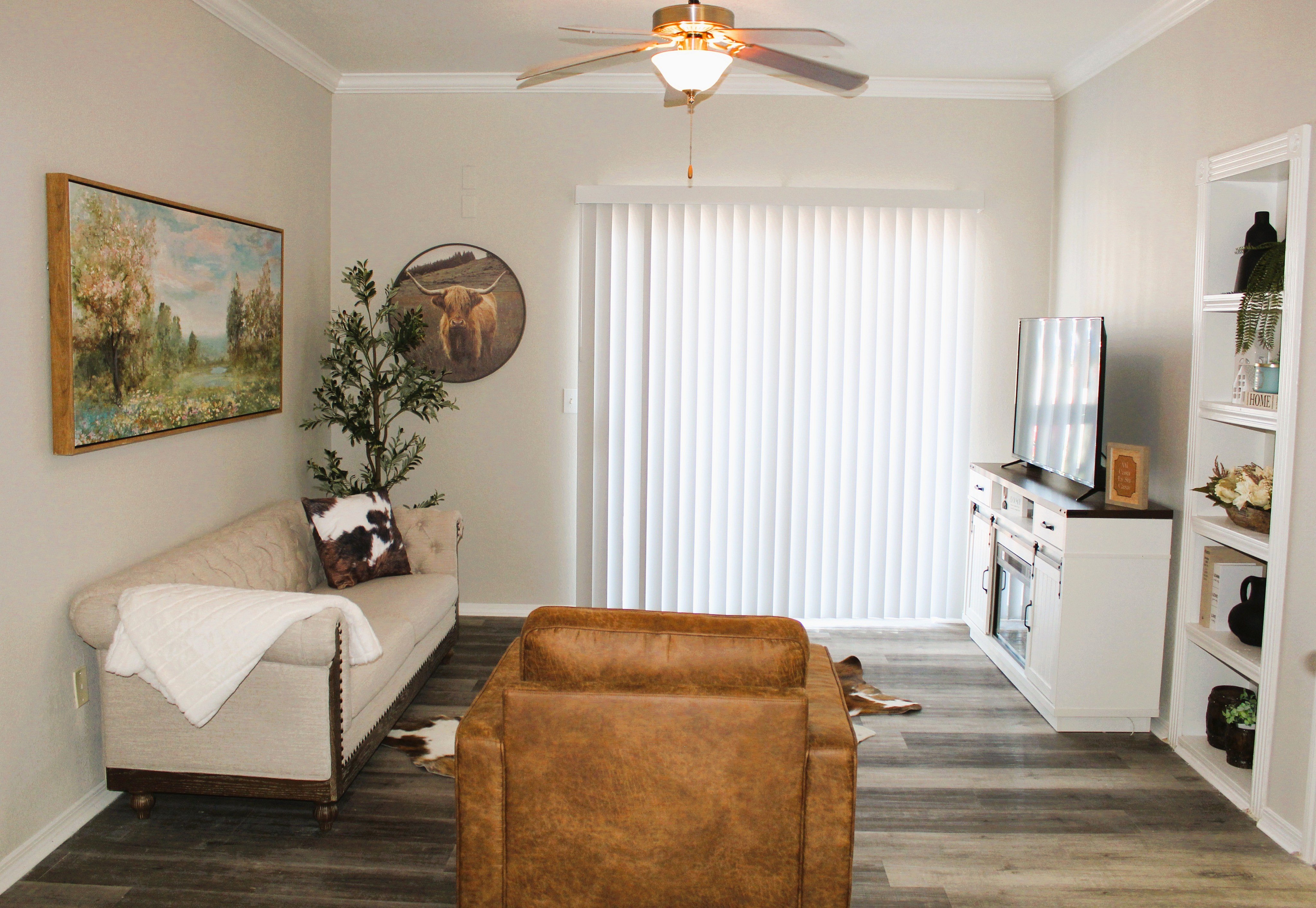 A living room with a brown leather chair and a painting of a landscape on the wall.