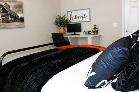 A black and white bedroom with a black bed and a white shelf with a plant on it.