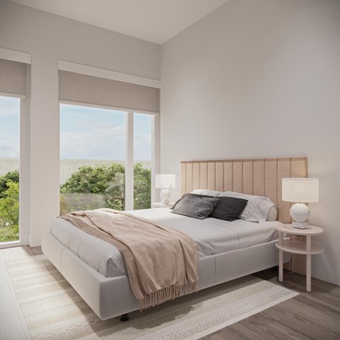 A bedroom with a large bed and a view of the trees outside the window.