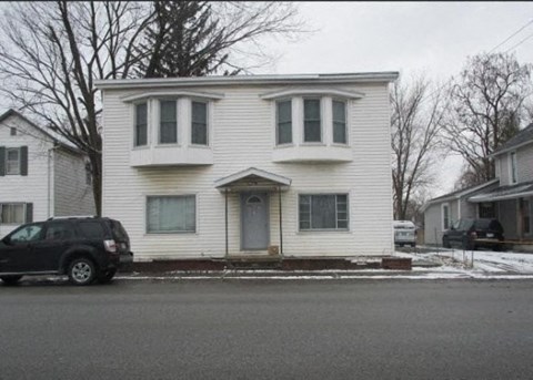 A white house with a black car parked in front.