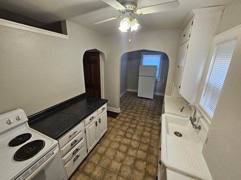 A kitchen with a black countertop and white appliances.