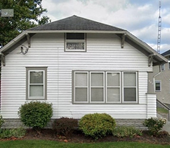 A white house with a grey roof and a window on the ground floor.