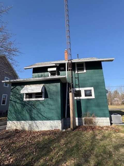 A green building with a white window and a brown door.