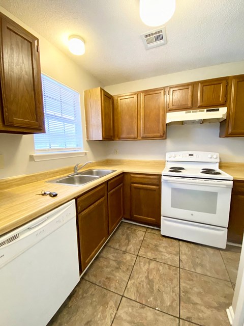 A kitchen with white appliances and wooden cabinets.