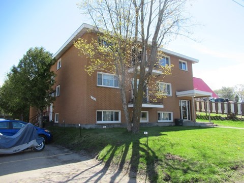 A red brick house with a tree in front of it.