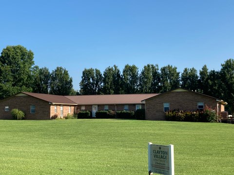 A sign in front of a house that says Clayton Village.