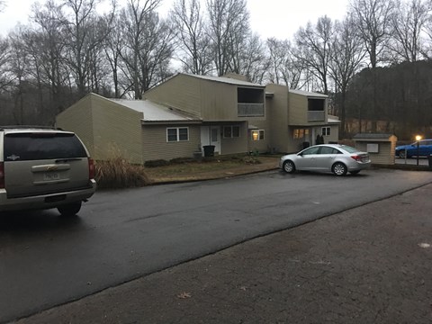 A silver car is parked on the side of a road in front of a building.