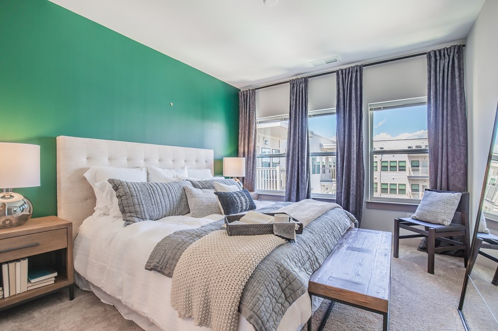 A bedroom with a large bed and a balcony overlooking the city.