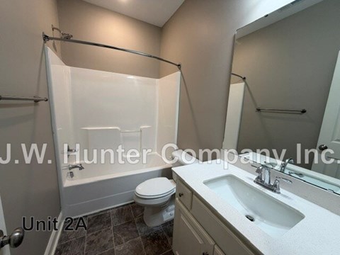 A bathroom with a toilet, sink, and shower.