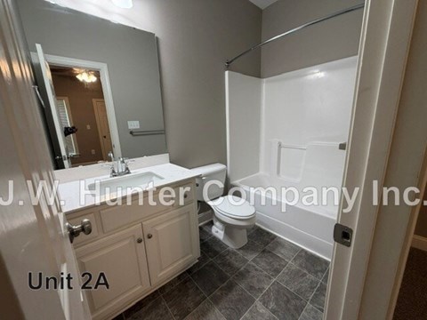A bathroom with a toilet, sink, and mirror.
