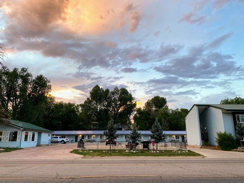 A parking lot with a building and trees in the background.