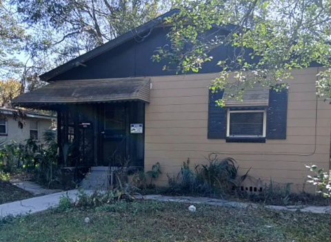 A small house with a brown roof and a black door.
