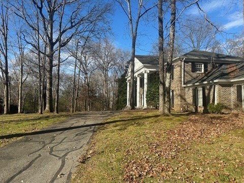 A house with a driveway and trees in the background.
