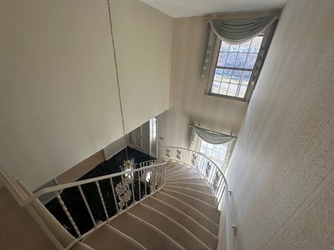A staircase with a metal railing and a window with curtains.