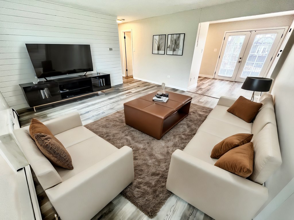 A modern living room with a white couch, a brown coffee table, and a flat screen TV.