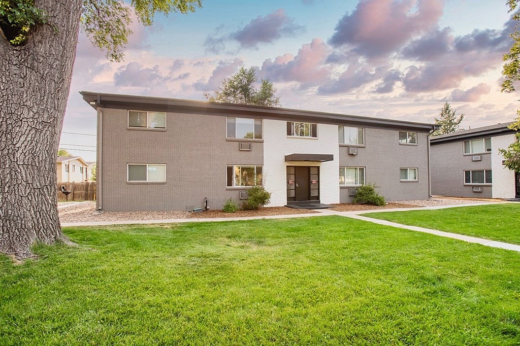 A patio with a couch, chairs, and a table with a bowl of fruit on it.