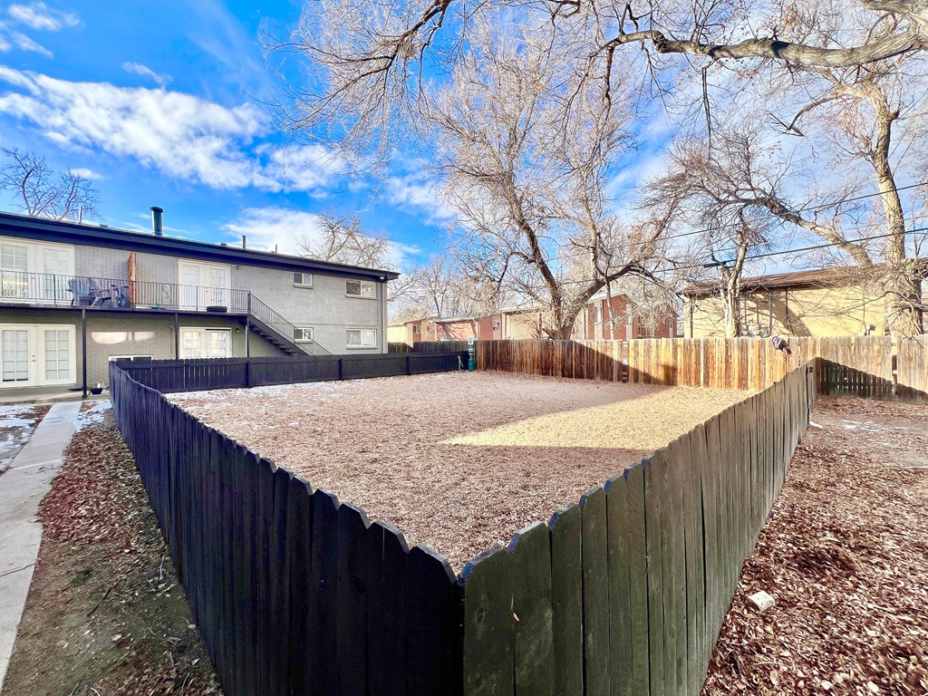 A backyard with a wooden fence and a brown gravel area.
