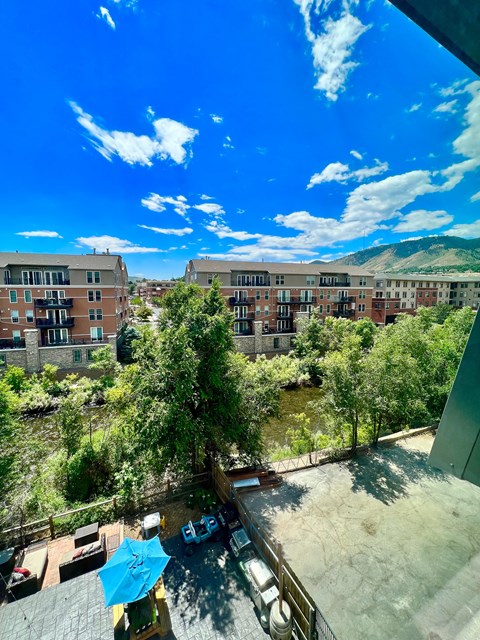 A view from a balcony overlooking a courtyard with trees and a mountain in the distance.