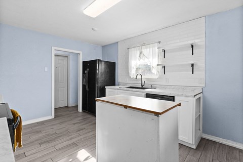A kitchen with a white counter and a black fridge.
