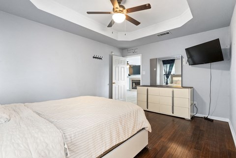 A bedroom with a bed, a dresser, and a ceiling fan.