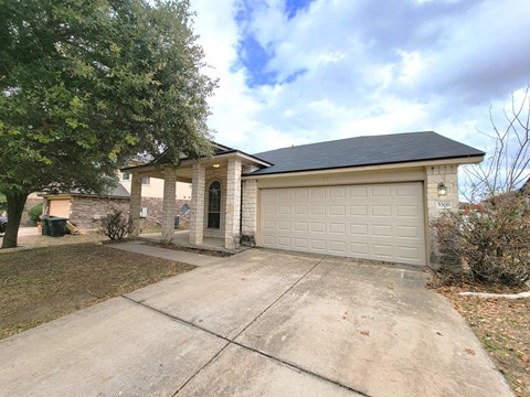 A house with a grey garage door and a black roof.